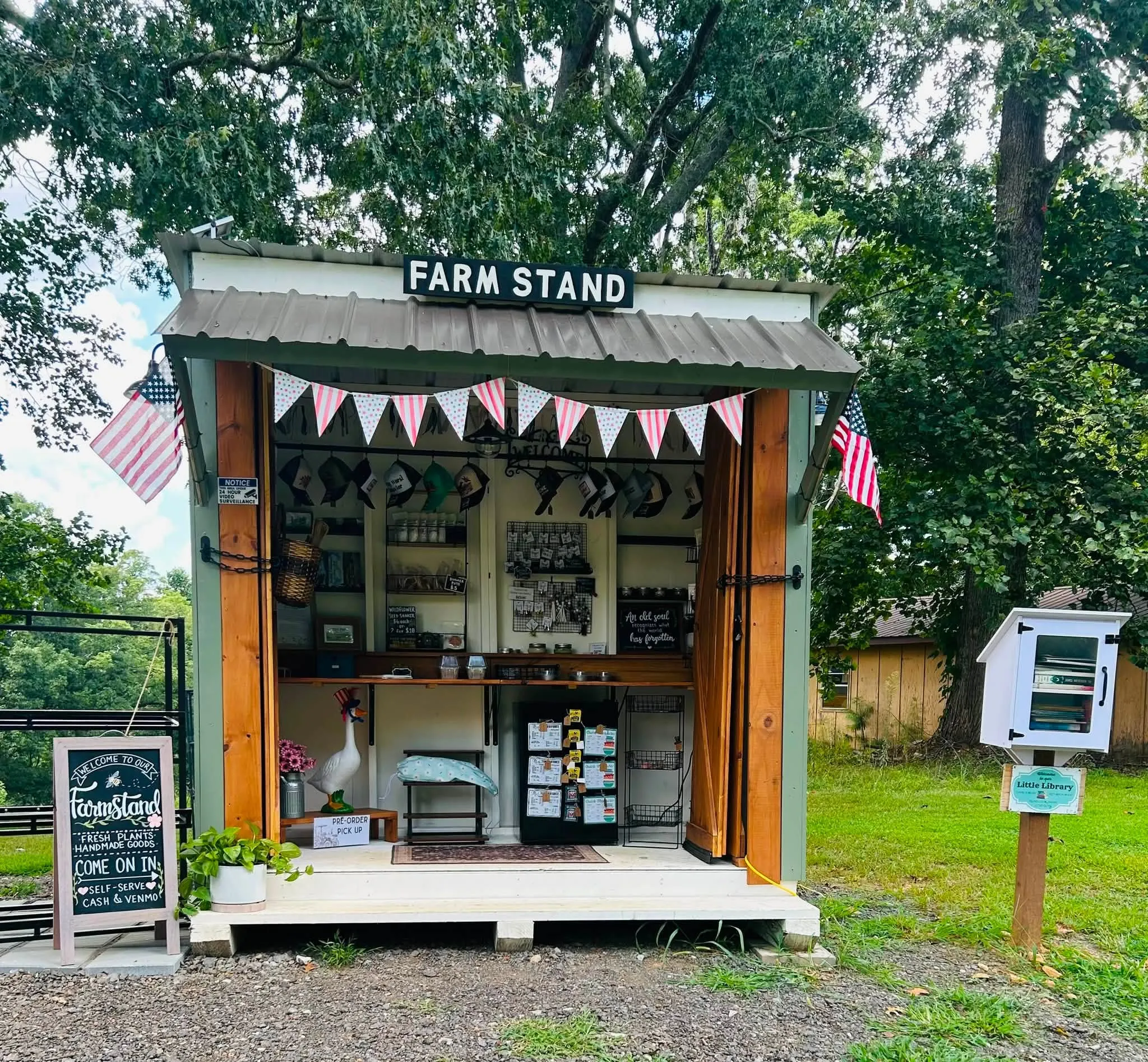 The Twisted Sisters Farm & Garden stand, a small covered shed with its doors open, stocked with plants, jars and handmade goods